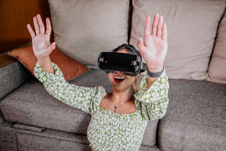 Asian Woman looking through virtual reality device at home. Augmented reality, game, future technology concept.VRの写真素材