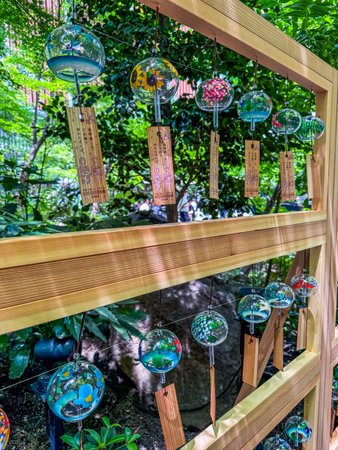 Decorative glass wind chimes with wooden tags hanging in rows against a green garden background