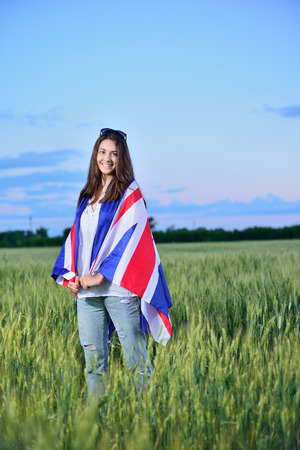 young smiling girl in a field of wheat. Flag of the Great Britain. The concept of learning English.の写真素材