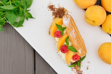 choux pastry with raspberry and apricot. Modern supply of gold and mint.