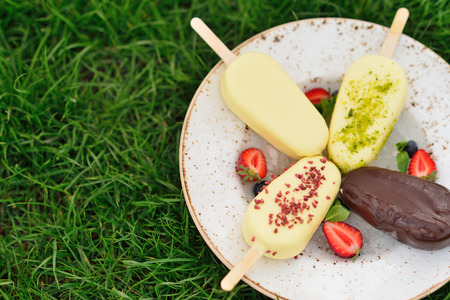 plate of ice cream on the grass. Glazed colorful popsicle. Summer grass. The freshness and coolness in the summer heat.の写真素材