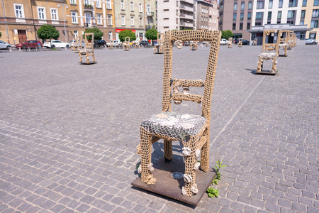 KRAKOW, POLAND - JUNE, 2017: Massive chair on cobblestone street in art installation in memory of Jewish ghetto. Krakow with popul. of 800,000 people has 2.35 mill. foreign tourists annuallyのeditorial素材