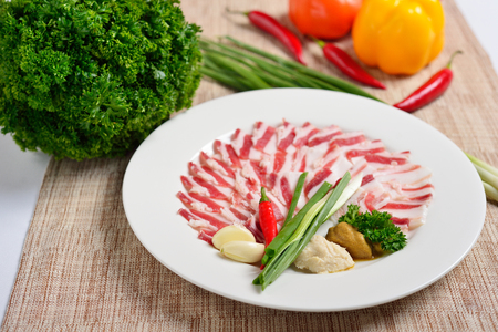 Plate with meat cutting, strips of bacon and sliced lard, sauce, greens. The concept of Russian Ukrainian restaurant.の写真素材