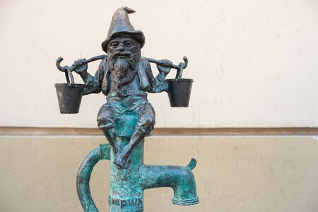 WROCLAW, POLAND - JUNE 17: Wroclaw street dwarf bronze statue with buckets sits on the water pump.のeditorial素材