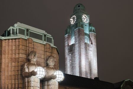 HELSINKI, FINLAND - NOVEMBER 2019: Helsinki, Finland. Night View Of Two Pairs Of Statues Holding The Spherical Lamps On Entrance To Helsinki Central Railway Station. Evening Or Night Illumination.のeditorial素材