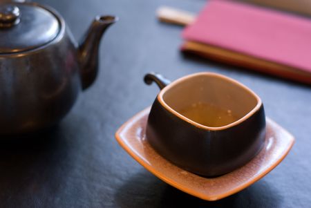 Teapot and teacup - focus on the front edge of the cup, shallow depth of field.の写真素材