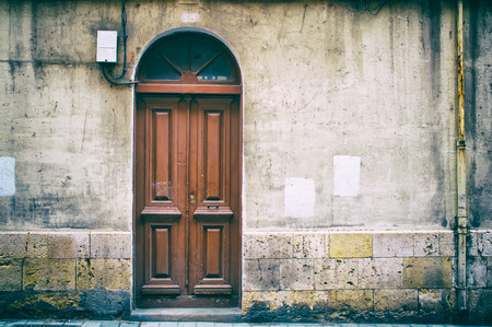 Vintage brown wooden door with grunge wall plaster background.の写真素材