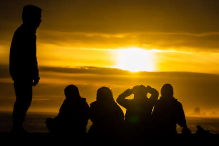 Man and a Group of Girls On the Beach at Sunset Silhouetteの写真素材