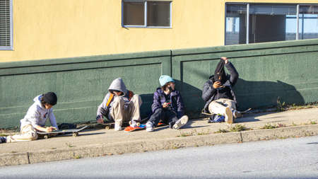 Bunch of Young Skater Punks Sitting on the Sidewalkの写真素材