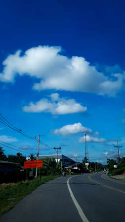 road with electric pole along the road on blue sky with the clouds background.