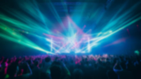 Blur crowd audience watching live show in concert hall or venue stadium with colorful lighting backgroundの素材