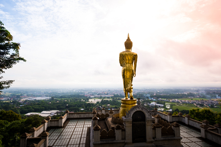 Golden Buddha statue standing on a mountain at Wat Phra That Khao Noi, Nan Province, Thailand with  wonderful skyの写真素材