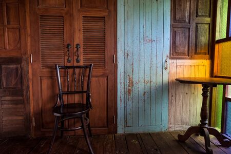 Old chair with wooden wall with pale blue door and wood round tableの写真素材