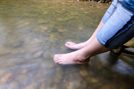 Lady feet steep  into the stream with the smooth waterの写真素材