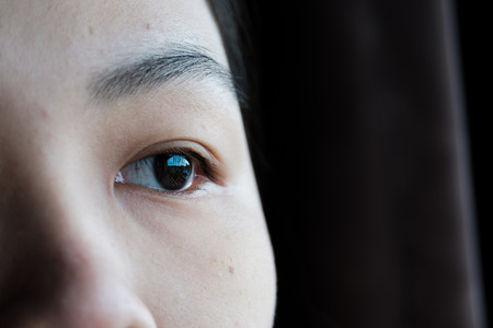 Closeup shot of lady half face looking outside windowの写真素材