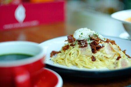 Spaghetti Carbonara with hot green tea in the red cupの写真素材