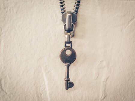Vintage key and metal zipper key chain on concrete wall, vintage effect