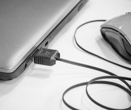 USB cable with mouse device plugged into laptop port, black and white effect (selective focus)