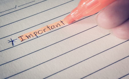 Important word writing and hand draw asterisk star sign on paper with orange highlighter pen, colored filter effectの写真素材