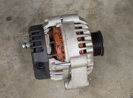 Cracked and old used alternator for the car on concrete floor