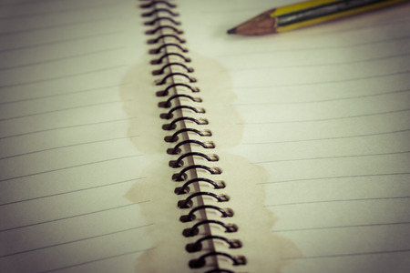 Pencil on dirty coffee stained opened line notebook, selective focus (colored filter effect)の写真素材