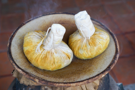 Hot two herbal compress balls are steaming on ancient coal stove with selective focusの写真素材