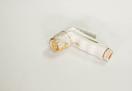 Old and dirty bidet shower head on white background with color filter effectの写真素材