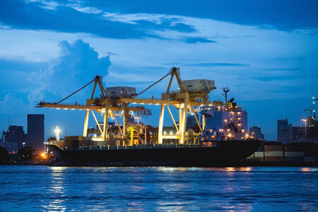twilight Container Cargo freight ship with working crane bridge in shipyard at dusk for Logistic Import Export background with working crane bridge in shipyard at dusk for Logistic Import Export backgroundのeditorial素材