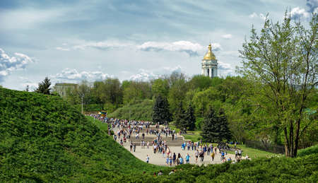 People walking in the park away on a day off. Summer green park. The church is far away. Green hills.の写真素材