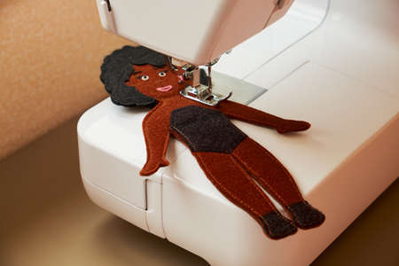 Handmade sewing toy dark-skinned girl. Felt doll with black hair. Mom's workplace.