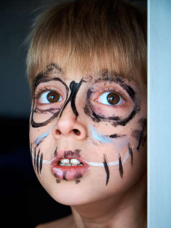 Painted face of a child on holiday. Surprised look of the boy. Portrait of a young man in a thoughtful mood.の写真素材