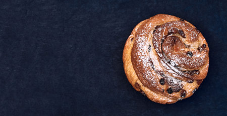 Christmas panettone with raisins, sprinkled with powdered sugar. Craffin isolated on dark...