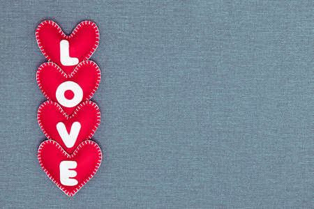 Red hearts on a gray background for Valentine's Day. Inscription Love. Handmade. Felt products.