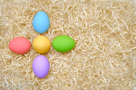 Colored chicken eggs in the form of a flower on wood shavings. Rainbow colors. Easter. Shooting from above close up. Pattern. Place for text.の写真素材