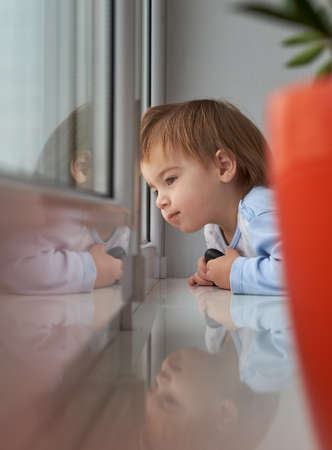 Children's Day. Little boy looks out the window. A small child is expecting someone.の写真素材