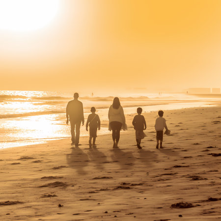 Silhouette of a family walking on the beach at sunset.の素材