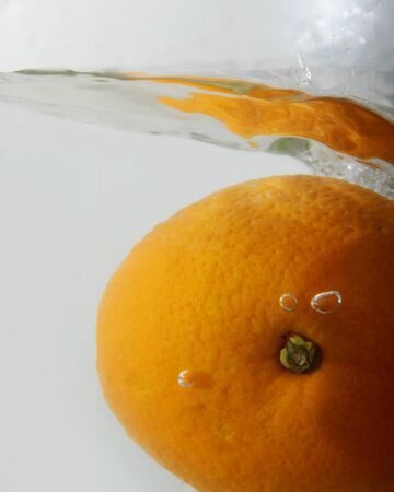 Orange drop into water on white background.の写真素材