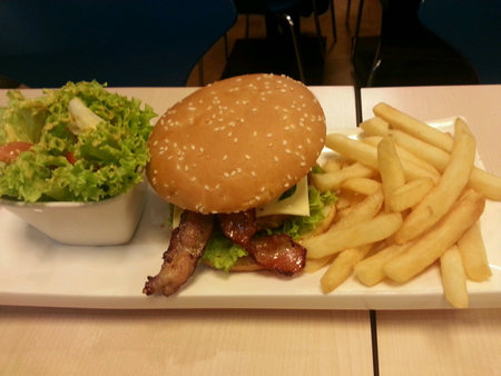 A plate of delicious bacon burger with a bowl of salad and friesの素材