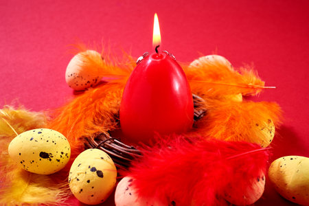 Close Up of a big red egg in the nest with colored feathers on the red background. Easter greeting card.の写真素材