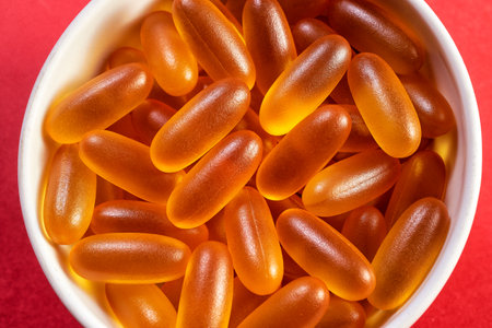 lots of yellow gelatin capsules on a red background. omega viramins, close-up, macro