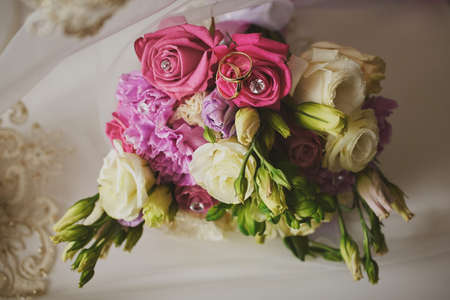 gold rings and a beautiful bridal bouquet of roses on the background. details, wedding traditions. close-up, macroの写真素材