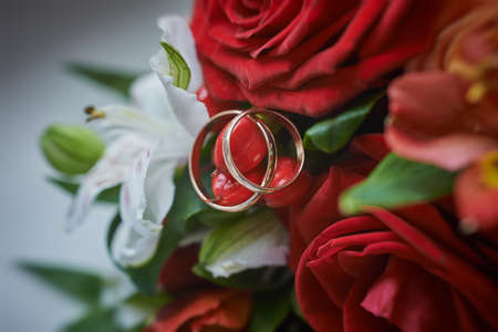 gold rings and a beautiful bridal bouquet of roses on the background. details, wedding traditions. close-up, macroの写真素材