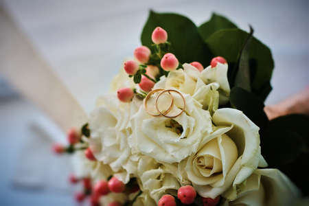 gold rings and a beautiful bridal bouquet of roses on the background. details, wedding traditions....
