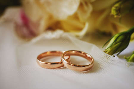 gold rings and a beautiful bridal bouquet of roses on the background. details, wedding traditions. close-up, macroの写真素材