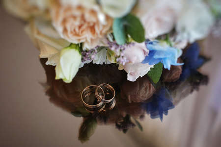 gold rings and a beautiful bridal bouquet of roses on the background. details, wedding traditions. close-up, macroの写真素材