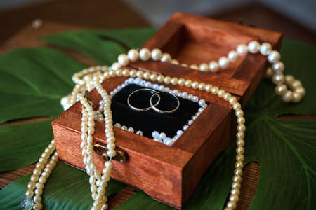 silver wedding rings in a wooden box decorated with pearls. vintage background