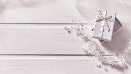 Jewelry made of beads, gift box, veil on a white wooden background. Copy space, top viewの写真素材