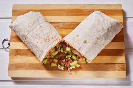 Vegan doner roll with beans in pink pita bread on a white wooden background. Close-up, macro