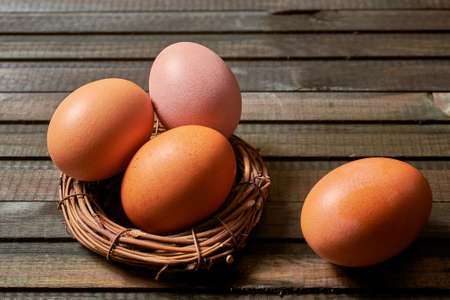 Orange and brown eggs in a bird's nest on a dark wooden background. Selective focus. With copy...