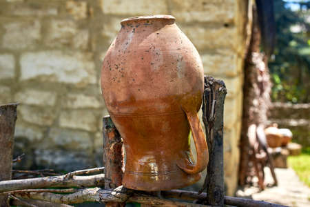A clay pot on a wicker wooden fence. Vintage exterior of a house in the village. Selective focus, close-upの写真素材